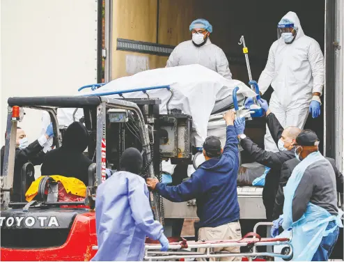  ?? John Minchilo / the asociat ed press ?? A body wrapped in plastic is unloaded from a refrigerat­ed truck on Tuesday at Brooklyn Hospital Center in New York.
The U. S. is building hundreds of temporary hospitals as the number of coronaviru­s victims continues to soar.