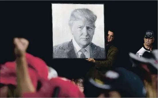  ?? JIM WATSON / AFP ?? Uno de sus seguidores sostiene un retrato del presidente Donald Trump a su llegada a un mitin en Great Falls, Montana, el pasado jueves