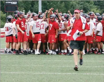  ??  ?? Russellvil­le coach Jeff Weaver heads downfield as offense and defense break the huddle and head off to their areas during preseason drills