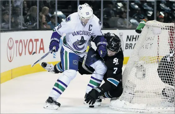  ?? — GETTY IMAGES ?? Henrik Sedin, left, of the Vancouver Canucks checks Paul Martin of the Sharks behind the San Jose net at the SAP Center Thursday in San Jose, Calif. The Canucks napped their nine-game losing streak with a 4-2 victory.