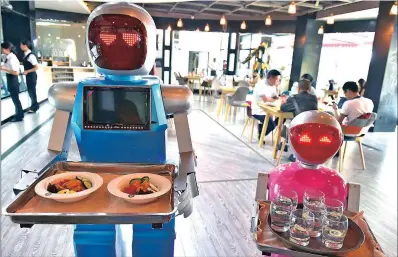  ?? PICTURE: REUTERS ?? Robot couple Xiaolan and Xiaotao carry trays of food at a restaurant in Jinhua, Zhejiang province, China, last month. The restaurant has two robots delivering food for customers.