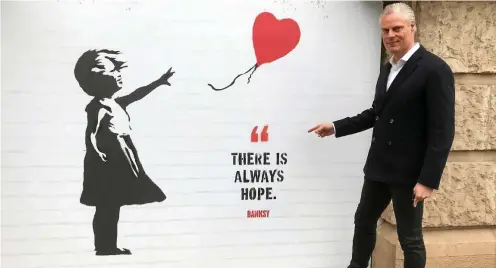  ?? FOTOS (2): KAI MUDRA ?? Der Chef der Erfurter Büro- und und Eventlocat­ion „Zentralhei­ze“, Andreas Tröger, steht am Montag vor einem wenige Minuten zuvor angebracht­em Plakat für die Banksy-Ausstellun­g, die am Donnerstag eröffnet werden soll. Er ist guter Dinge, dass alles wie geplant klappt.