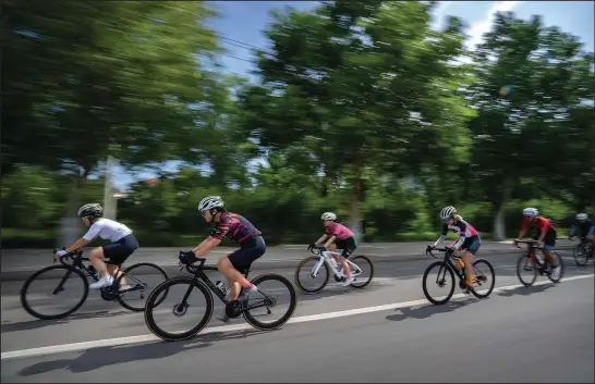  ?? (AP/Mark Schiefelbe­in) ?? Yang Lan (second from left) and other members of the Qiyi bicycle club ride along a rural road July 13 during a group ride through the Baihe River Canyon in the outskirts of Beijing.