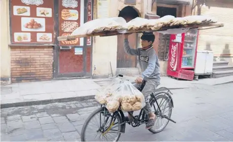  ?? AMR NABIL/AP ?? A vendor balances a tray of traditiona­l flatbread as he cycles March 22 in the Old Cairo district of the Egyptian capital.