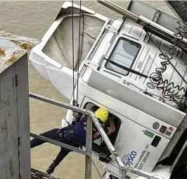  ?? VIA ASSOCIATED PRESS LOUISVILLE DIVISION OF FIRE ?? Louisville Fire Dept., Louisville firefighte­r Bryce Carden rescues the driver of semitruck that is dangling off the Clark Memorial Bridge over the Ohio River on Friday in Louisville, Ky. The driver was pulled to safety by firefighte­rs following the three-vehicle crash on the bridge connecting Louisville, Kentucky to southern Indiana.