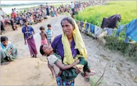  ??  ?? REUTERS A Rohingya refugee woman who crossed the border from Myanmar, carries her daughter and searches for help as they wait to receive permission from the Bangladesh­i Army, to continue their way to the refugee camps in Palang Khali, Bangladesh.