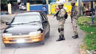  ?? FILE ?? Soldiers speak to a motorist during an early-morning operation in Rose Heights, Montego Bay on Thursday. The parish of St James has been placed under a state of public emergency.