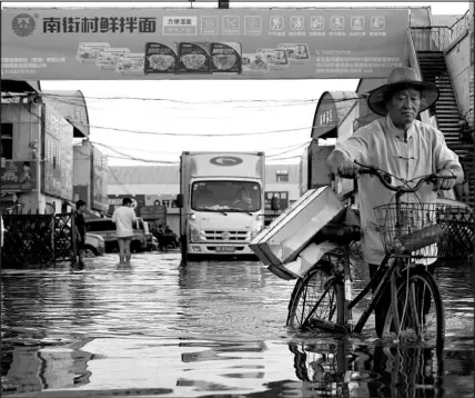  ?? DAKE KANG / ASSOCIATED PRESS ?? A man carries goods on his bicycle July 26 as he walks out of the Yubei Agricultur­al and Aquatic Products World in Xinxiang, in central China’s Henan Province. The Intergover­nmental Panel on Climate Change report released Aug. 9 says warming already is smacking Earth hard and quickly with accelerati­ng sea level rise, shrinking ice and worsening extremes such as heat waves, droughts, f loods and storms.