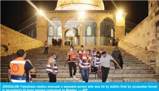  ?? — AFP ?? JERUSALEM: Palestinia­n medics evacuate a wounded person who was hit by bullets fired by occupation forces in Jerusalem’s Al-Aqsa mosque compound on Monday.