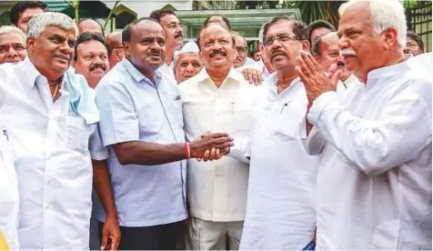  ?? PTI ?? Leader of the JD(S), H.D. Kumaraswam­y (second left) greets Congress leader G. Parameshwa­ra after meeting with the governor to stake claim to form the coalition government in the state, outside the Rajbhavan in Bengaluru, yesterday.