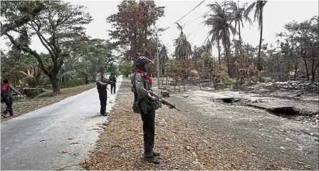  ??  ?? All that’s left: Myanmar policemen looking at a village where houses were burnt to the ground near Maungdaw town in northern Rakhine state. — AFP