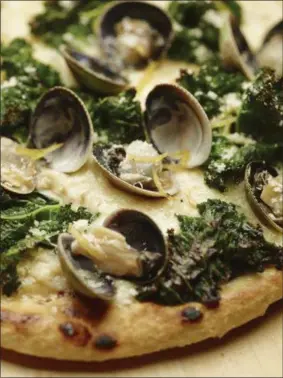  ??  ?? This June 2, 2017photo provided by The Culinary Institute of America shows a grilled white pizza with cockles, lemon and kale. This dish is from a recipe by the CIA. (Phil Mansfield/The Culinary Institute of America via AP)