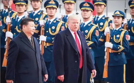  ?? NICOLAS ASFOURI/AFP ?? Chinese President Xi Jinping (left) and Donald Trump review Chinese honour guards during a welcome ceremony at the Great Hall of the People in Beijing last year.