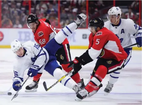  ?? SEAN KILPATRICK/THE CANADIAN PRESS ?? Mitch Marner had a rough welcome to the NHL, getting upended by Ottawa’s Mike Hoffman, second from left, in the first period of the Leafs opener.