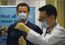  ?? JAE C. HONG — STAFF PHOTOGRAPH­ER ?? Gov. Gavin Newsom watches as the Pfizer-BioNTech COVID-19 vaccine is prepared by Director of Inpatient Pharmacy David Cheng at Kaiser Permanente Los Angeles Medical Center in Los Angeles on Monday