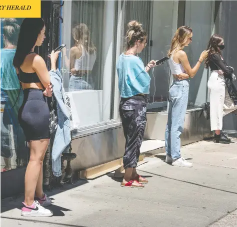  ?? PETER J THOMPSON / FOR NATIONAL POST ?? Shoppers maintain physical distance at a store lineup in Toronto on Monday. Some countries have decreased physical distancing recommenda­tions.