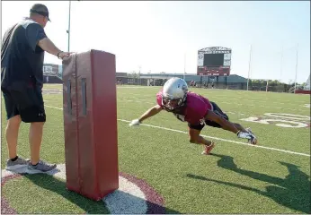  ?? Graham Thomas/Siloam Sunday ?? Siloam Springs head coach Brandon Craig holds a tackling dummy as senior cornerback Primo Agbehi dives in for a tackling drill at football practice Thursday at Panther Stadium.