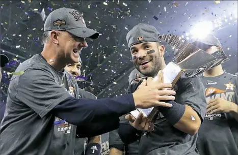  ?? David J. Phillip/Associated Press ?? Houston manager A.J. Hinch and star second baseman Jose Altuve hold the American League championsh­ip trophy after the Astros’ 4-0 defeat of the New York Yankees on Saturday night in Houston.