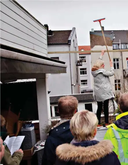  ?? FOTO: VEGARD DAMSGAARD ?? Grete Strømstad bruker vaskekoste­n til å vise høyden på naboens planlagte tilbygg. By- og miljøutval­get står på verandaen hennes og får sympati for henne.