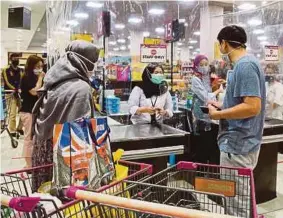  ?? (Foto AFP) ?? Pelanggan pasar raya di Tangerang, Banten mengamalka­n penjarakan sosial ketika membuat bayaran di kaunter.