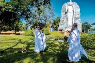  ??  ?? Tissus blancs et crâne rasé : des nonnes se recueillen­t durant une halte, sur la route de Sigiriya…