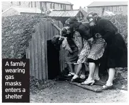  ??  ?? A family wearing gas masks enters a shelter