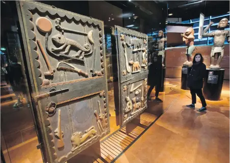  ??  ?? A visitor walks past a door of the king’s palace from the Dahomey kingdom dating from the 19th century at the Quai Branly museum in Paris. Experts estimate up to 90 per cent of African art is outside the continent, including statues, thrones and manuscript­s.