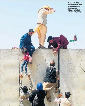  ??  ?? Desperate Afghans scale a border wall at Hamid Karzai Internatio­nal Airport in Kabul. Photo / Getty Images