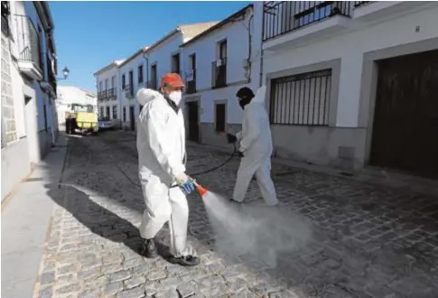  ?? VALERIO MERINO ?? Dos operarios desinfecta­n una calle vacía de Añora, municipio del norte que está confinado