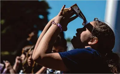  ?? Josie Norris/staff photograph­er ?? A young person looks through solar eclipse glasses at the Oct. 14 annular eclipse in Kerrville. If you plan to travel to the Hill Country for the full eclipse experience, be prepared for traffic jams that go on for miles, and food, gas and ATM cash shortages.