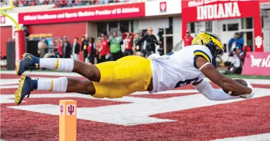  ?? AP ?? Cornelius Johnson (6) dives into the end zone during the second half of Michigan’s victory. Assistant coach Mike Hart was hospitaliz­ed after collapsing on the sideline.