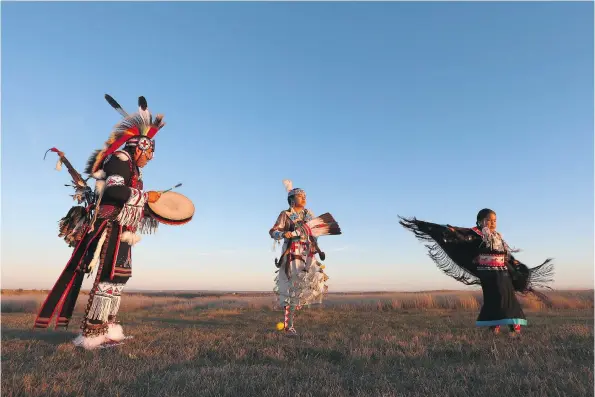  ?? PHOTOS: MICHELLE BERG ?? TJ Warren keeps a steady beat for his daughters Omiyosiw Nazbah Warren and Kiihibaa Acahkos Warren to dance to during sunset at Wanuskewin Heritage Park. Both of his daughters have been active in powwow from a young age. The family travels extensivel­y,...