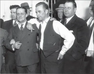  ?? THE ASSOCIATED PRESS ?? John Dillinger, center, strikes a pose with Lake County prosecutor Robert Estill, left, in the jail at Crown Point, Ind., in 1934. Dillinger was awaiting trial for the murder of police officer Willliam Patrick O’Malley when Dillinger robbed the First...