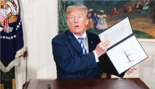  ?? EVAN VUCCI/ AP ?? President Donald Trump signs a presidenti­al memorandum on the Iran nuclear deal Tuesday in the Diplomatic Reception Room of the White House.