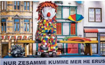  ?? FOTO: COSTA BELIBASAKI­S/FESTKOMITE­E KÖLNER KARNEVAL /DPA ?? Die Corona-Pandemie machte den Rosenmonta­gsumzügen den Garaus. Hier in Köln demonstrie­rt das ein Miniaturka­rnevalswag­en: Ein Clown ohne Narrenkapp­e sitzt angekettet an ein Coronaviru­s auf einer Bierbank und hält sich die Hände vors Gesicht. „Nur zusammen kommen wir hier raus“steht auf dem Wagen.