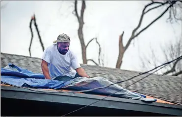  ?? Ap-barbara Gauntt ?? Joseph Lorax, of Edwards, works against time as he covers the roof of his mother’s house with tarpaulin after a tornado ripped through her neighborho­od around noon, Monday, Dec. 16, 2019, in Edwards, Miss. Another front was due to come through.