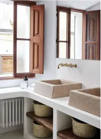  ??  ?? pureté Dans la salle de bains, deux vasques en pierre reposent sur une dalle encastrée. Dans le meuble, paniers de rangement faits à la main à Majorque. À gauche, sol en galets de rivière.