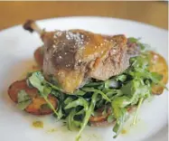  ??  ?? The duck leg confit sits on an arugula salad and roasted ratte potatoes.