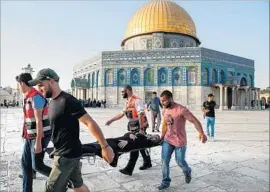  ?? Ahmad Gharabli AFP/Getty Images ?? PALESTINIA­N PARAMEDICS carry an injured woman on a stretcher past the Dome of the Rock after clashes broke out inside the Al Aqsa Mosque compound.