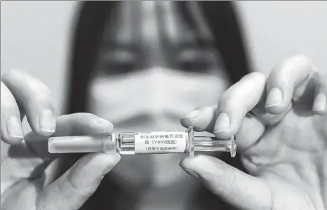  ?? ZHANG YUWEI / XINHUA ?? A China National Biotech Group Co Ltd employee displays a COVID-19 inactive vaccine, which is under developmen­t and trials, at the company’s research institute in Wuhan, capital of Hubei province, on April 10.