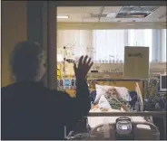  ??  ?? Nurse Susan Morales waves to David Feinour, a 71-year-old covid-19 patient, at St. Jude Medical Center. “We still have emotions,” said Morales, who has been a nurse for 42 years. “The day you don’t is the day you should get out of nursing. That’s what I would tell my students.”