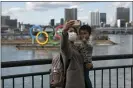  ?? JAE C. HONG — THE ASSOCIATED PRESS FILE ?? A woman with a young boy takes a selfie with the Olympic rings, in Tokyo’s Odaiba district.