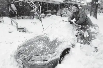  ?? Laurie Skrivan / Associated Press ?? Jeff Clifford digs out his girlfriend’s car from beneath snow Saturday in St. Louis. A winter storm swept the region, snarling traffic and leaving thousands without power.