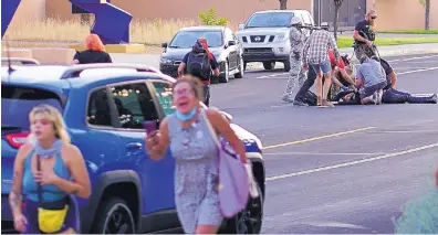  ?? ADOLPHE PIERRE-LOUIS/JOURNAL ?? People run for cover as a man lies in the middle of the intersecti­on of Mountain and 20th after being shot Monday night as protesters tried to take down a statue of Juan de Oñate outside the Albuquerqu­e Museum in Old Town.