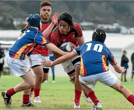  ?? PHOTO: JOE SERCI/WELTEC ?? ishop Viard College’s Philip Filipo is tackled by Tawa College defenders on Saturday. Viard won 17-13 to qualify for premier one.