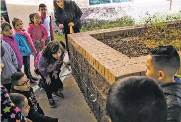  ??  ?? First-graders in Rita Rios-Baca’s class watch Nov. 19 as a bubble drifts around a brick wall, in a demonstrat­ion of wind and air patterns.