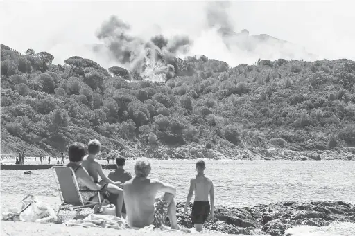  ?? — Gambar AFP ?? MUSNAH: Pelancong yang berkelah di tepi pantai terpaku melihat kebakaran hutan di La Croix-Valmer dekat Saint-Tropez, kelmarin.