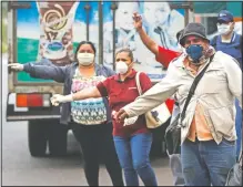  ??  ?? Masked commuters flag down a bus Monday in Asuncion, Paraguay. While the government extended the quarantine to April 21 to help contain the spread of the new coronaviru­s, some workers like those in constructi­on and food industries, are authorized to work.
(AP/Jorge Saenz)