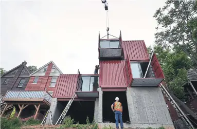  ?? STORSTAC ?? NOW: A crane lowers the sixth of eight re-fabricated and painted shipping containers to create Geoffey Young’s home.