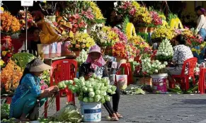  ?? — AFP ?? Full bloom: Vendors preparing flowers for sale at a market in Phnom Penh.